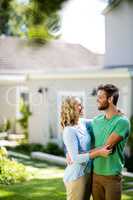 Couple hugging in yard against house