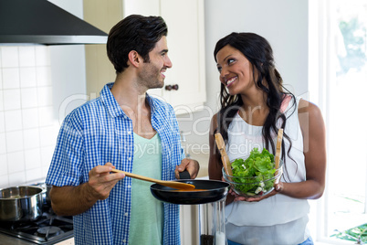 Young couple cooking food together in kitchen