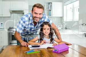 Happy father helping daughter with homework in kitchen