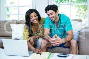 Happy couple with laptop discussing on bills