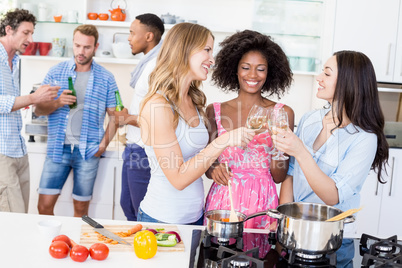 Friends toasting wine glasses in kitchen