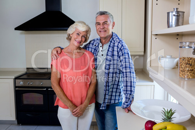 Smiling senior man with woman standing in kitchen at home