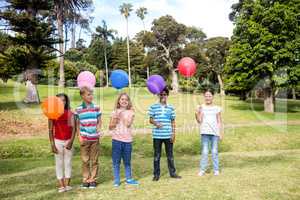 Children standing with balloons in the park