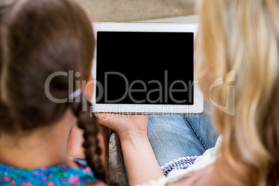 Rear view of mother and daughter with digital tablet