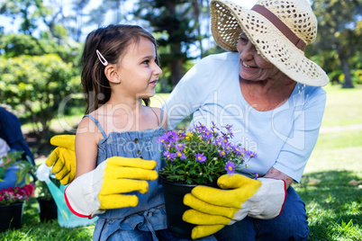 Grandmother and granddaughter holding a flower pot while gardeni