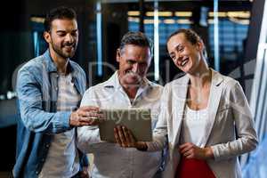 Businessmen and businesswoman discuss using digital tablet