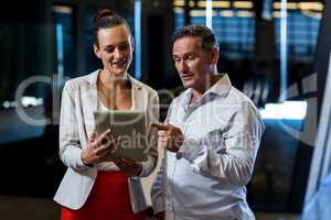 Businessman and businesswoman discuss using digital tablet