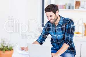Young man paying his bill online with laptop