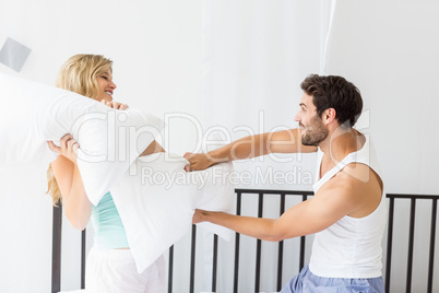Young couple having a pillow fight Young couple having a pillow fight