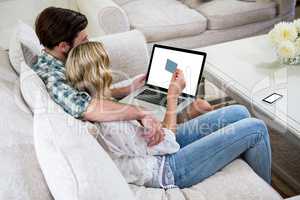 Couple shopping online while sitting on sofa