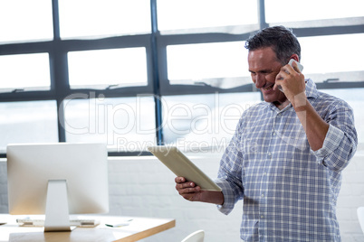 Man looking at digital tablet while talking on phone