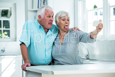 Senior couple making faces while taking selfie through phone