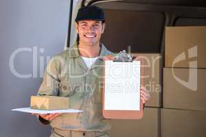 Happy delivery man holding cardboard box and clipboard