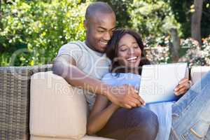 Young couple relaxing on the sofa and using digital tablet