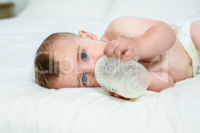 Baby boy drinking milk while lying on bed at home
