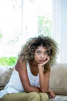 Tensed woman sitting on bed in living room