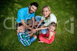 Family huddling hands while sitting on grass at yard
