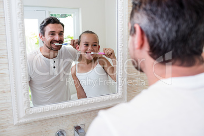 Father and daughter brushing their teeth in the bathroom