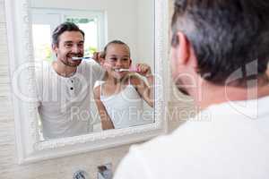 Father and daughter brushing their teeth in the bathroom