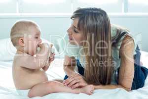 Woman playing with baby boy on bed