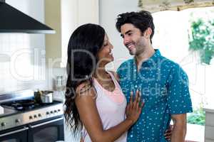 Young couple embracing face to face in kitchen