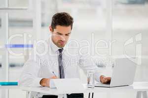 Businessman using laptop and taking notes