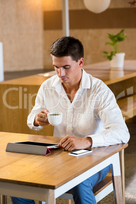 Man using digital tablet while having cup of coffee