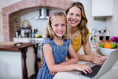 Portrait of mother and daughter using laptop in kitchen Portrait of mother and daughter using laptop in kitchen