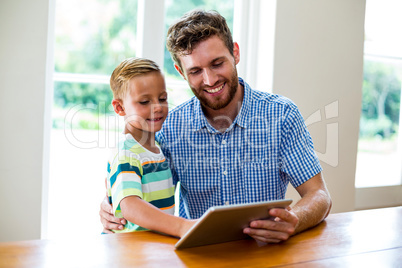Father and son looking into digital tablet at home Father and son looking into digital tablet at home