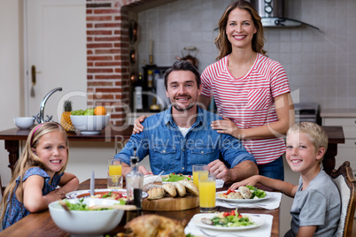 Portrait of happy family having meal in kitchen