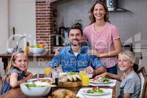 Portrait of happy family having meal in kitchen