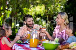 Mother offering salad while family sitting at table