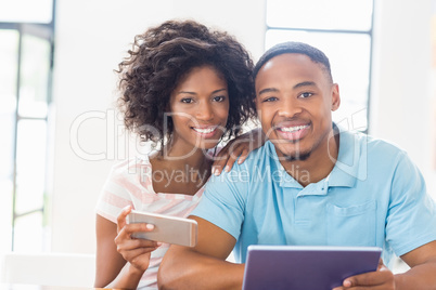 Happy couple using mobile phone and digital tablet