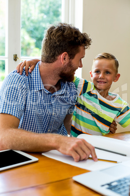 Smiling father teaching son at home