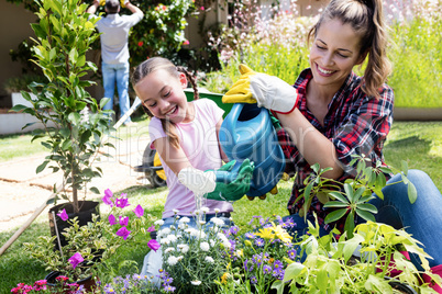 Mother and daughter watering the plants in the garden