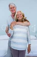 Happy senior couple embracing in bedroom at home
