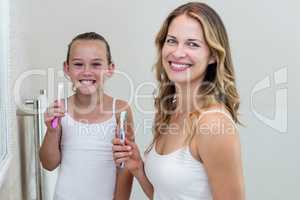 Portrait of happy daughter and mother holding a toothbrush in th