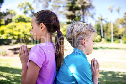 Siblings praying in park