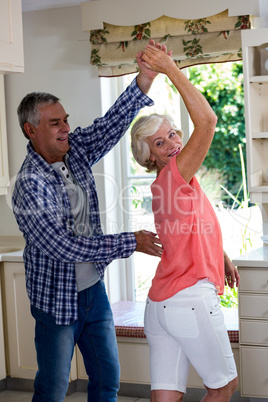 Senior couple dancing in kitchen at home