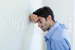 Depressed man leaning his head against a wall