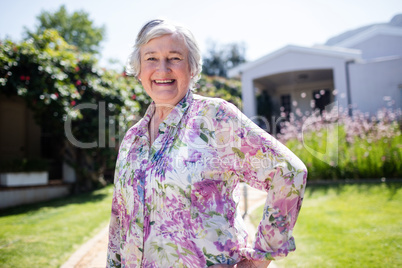 Portrait of happy senior woman standing in garden