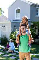 Smiling father carry daughter on shoulders in yard