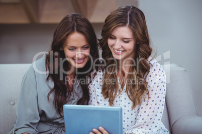 Two beautiful women using a digital tablet in living room