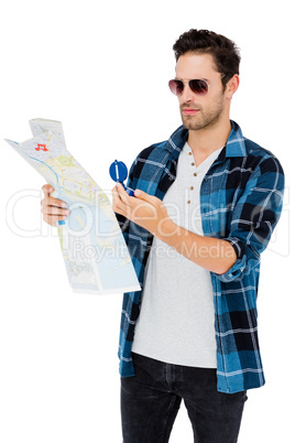 Young man in sunglasses looking at map and compass