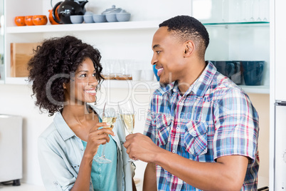Happy couple toasting champagne glass in kitchen