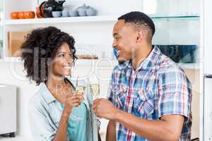 Happy couple toasting champagne glass in kitchen
