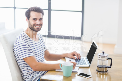 Man smiling at camera while writing notes