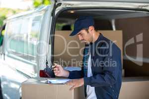 Side view of delivery person writing in clipboard
