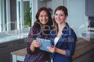 Two beautiful women using digital tablet in kitchen