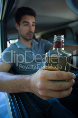 Slumped young man holding alcohol bottle